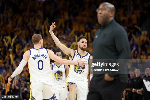 Klay Thompson of the Golden State Warriors reacts next to Sacramento Kings head coach Mike Brown after he made a basket at the end of the third...