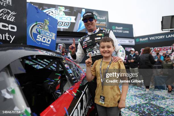 Kyle Busch, driver of the McLaren Custom Grills Chevrolet, and his son, Brexton, affix the winner's decal to the winning car in Victory Lane after...