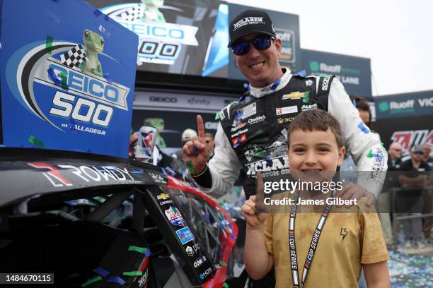 Kyle Busch, driver of the McLaren Custom Grills Chevrolet, and his son, Brexton, affix the winner's decal to the winning car in Victory Lane after...