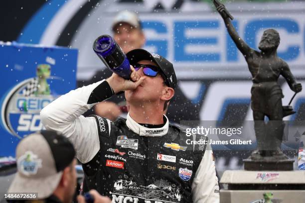 Kyle Busch, driver of the McLaren Custom Grills Chevrolet, celebrates by drinking champagne in victory lane after winning the the NASCAR Cup Series...