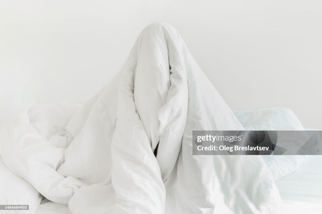 Person hiding under blanket and don't want to wake up. Insomnia, sleeplessness concept