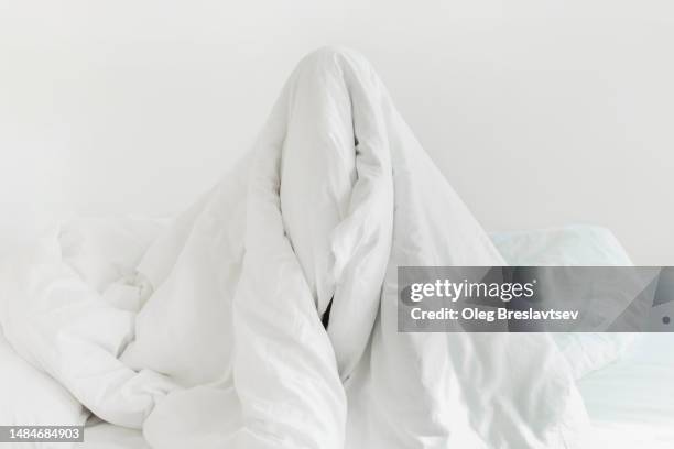 person hiding under blanket and don't want to wake up. insomnia, sleeplessness concept - manta-ropa-de-cama fotografías e imágenes de stock