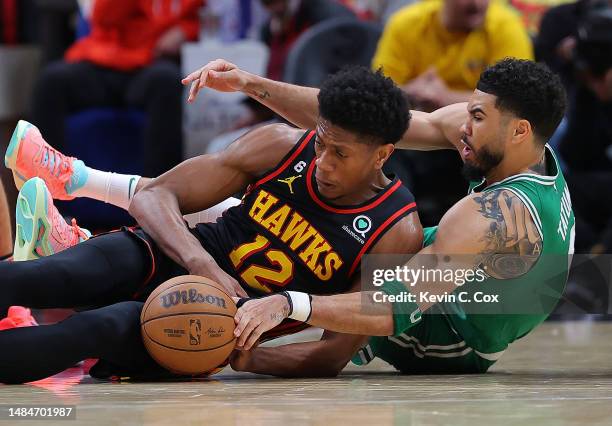 Jayson Tatum of the Boston Celtics battles for a loose ball against De'Andre Hunter of the Atlanta Hawks during the third quarter of Game Four of the...