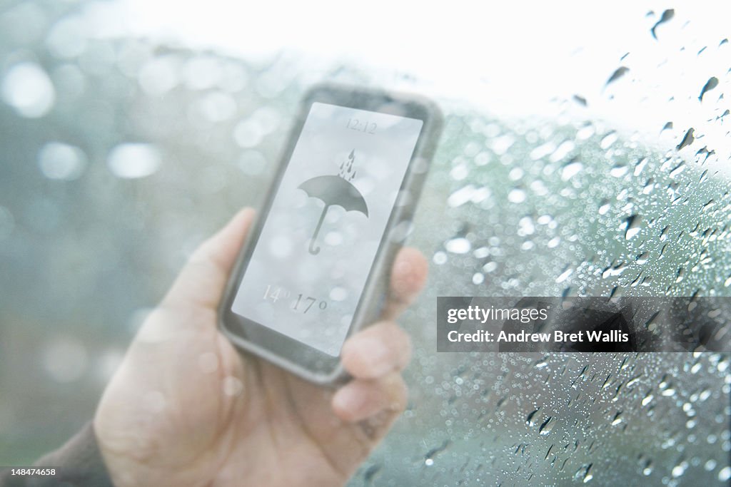 Mobile weather text behind rain soaked window