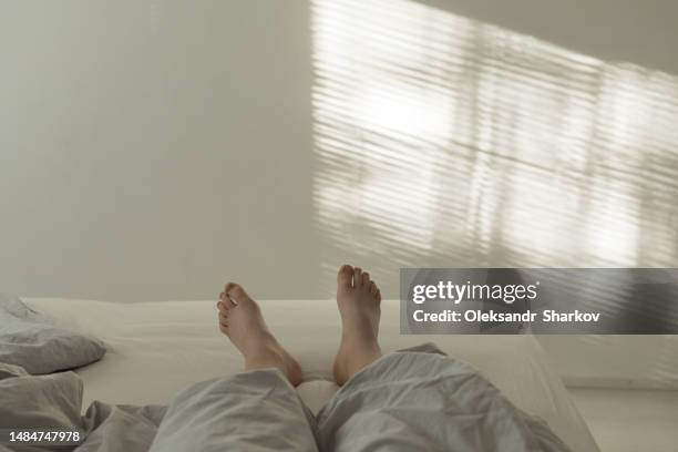 women with bare feet laying in bed - womans bare feet fotografías e imágenes de stock