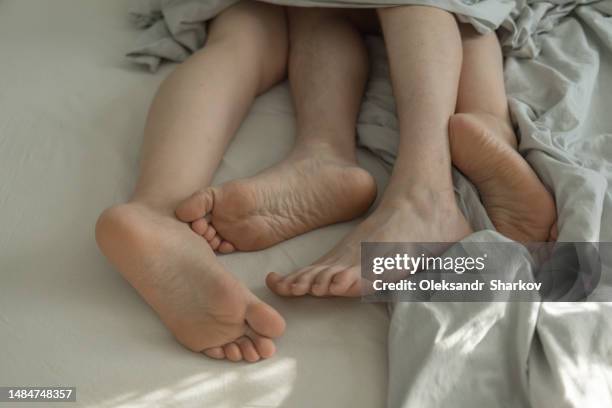 male and female feet in bed under blankets - woman lying on stomach with feet up stock pictures, royalty-free photos & images