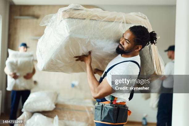 young black mover carrying furniture in a new apartment. - mover stock pictures, royalty-free photos & images