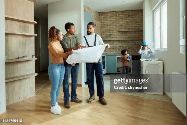 padres negros y trabajadores manuales analizando planos en el apartamento. - renovación del hogar fotografías e imágenes de stock