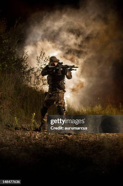 a warrior holding a gun pointing at something at a war field - weather alert stock pictures, royalty-free photos & images