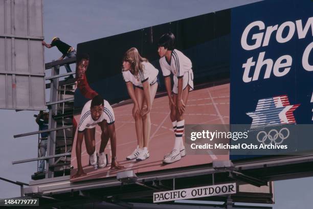 Billboard featuring American athlete Rafer Johnson, with the slogan 'Grow With The Olympics, Los Angeles 1984 Olympics' being raised into position...