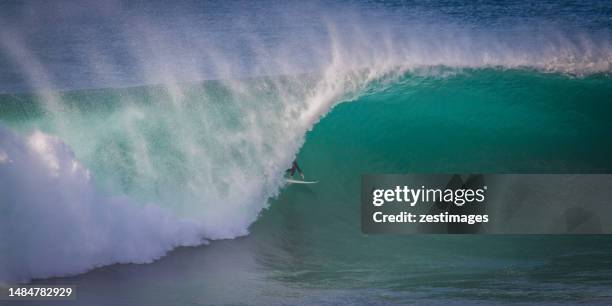 surfer surfing a giant barrel wave, barrack point, shellharbour, new south wales, australia - wellentunnel stock-fotos und bilder