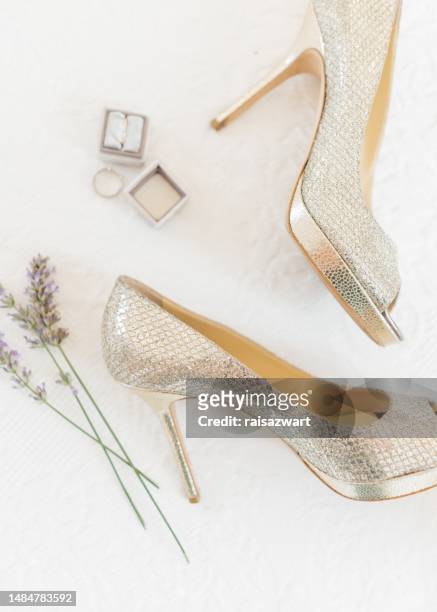 overhead view of a wedding ring, engagement ring, high heel platform stiletto shoes and lavender - gold shoe foto e immagini stock
