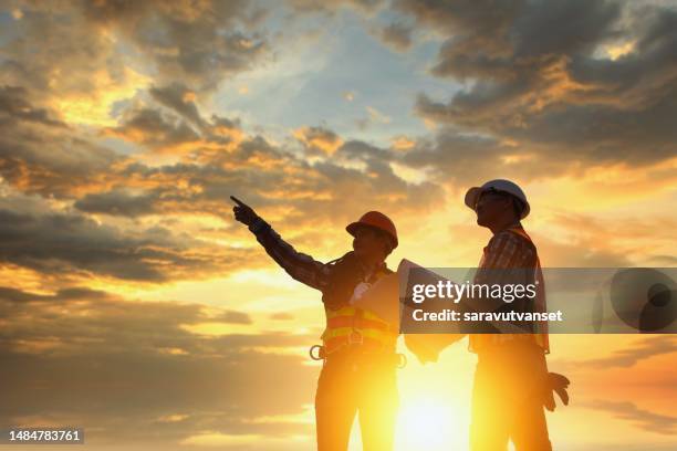 silhouette of two construction engineers standing on a building site supervising a building project at sunset, thailand - asian architect 40 imagens e fotografias de stock