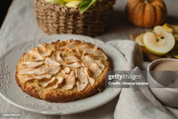 close-up of a homemade healthy low carb apple pie, apples, pumpkin and a cup of coffee on a table - apple pie stock pictures, royalty-free photos & images