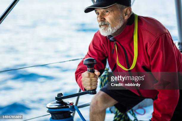 skipper holding handle on winch of genoa sail on sailboat - boat captain stockfoto's en -beelden