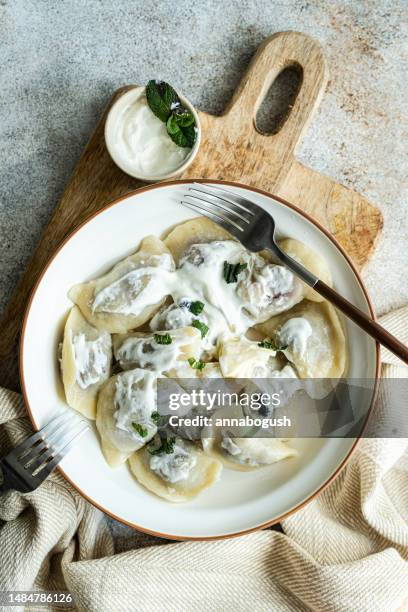 overhead view of a plate of traditional ukrainian sour cherry dumplings (vareniki) with sour cream and mint - ukrainian culture stock pictures, royalty-free photos & images