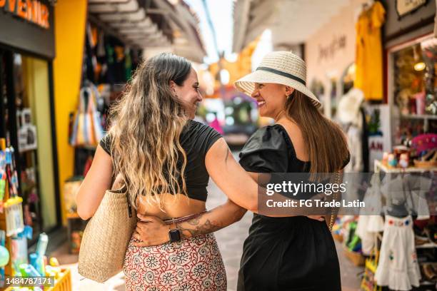 lesbian traveler couple embracing while having a walk on an outdoors market - mexican street market stock pictures, royalty-free photos & images