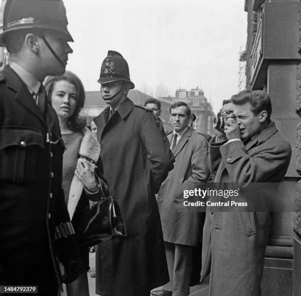 Christine Keeler surrounded by policemen and a photographer outside the Old Bailey courthouse, London, April 1st 1963. She had a hearing with a judge...