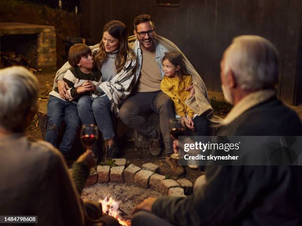 happy extended family enjoying by the bonfire at night. - boy warming up stock pictures, royalty-free photos & images