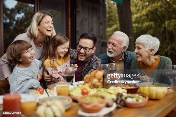 cheerful extended family having fun during lunch on a terrace. - mother son daughter stock pictures, royalty-free photos & images