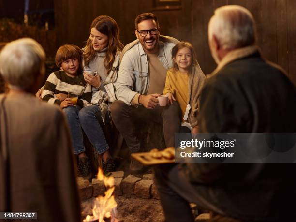 happy multi-generation family enjoying by the fire at night. - boy warming up stock pictures, royalty-free photos & images