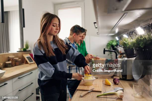 generation z teenagers making salad in kitchen - young cook imagens e fotografias de stock
