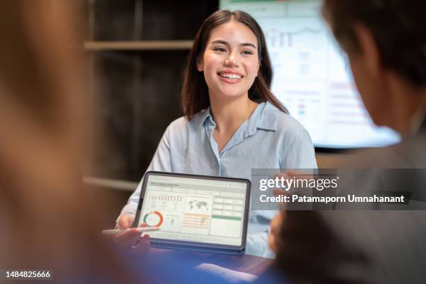 tracking and analyzing competitor data drive business growth effectively. business leader team using digital tablet show the historical statistic data on info graphic screen to attendees in the board meeting room with smile. analysis data to improve or de - results show stockfoto's en -beelden