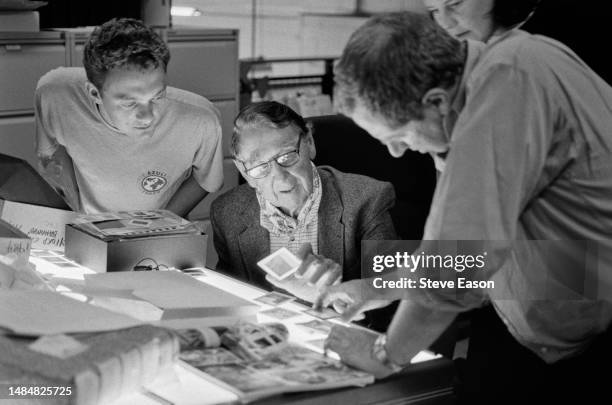 The American photographer Slim Aarons looks through images from his collection with London gallerist Michael Hoppen and Hulton Getty staff members...