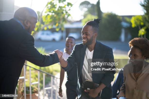 pastor begrüßt lächelnden schwulen mann in der kirche - pastor stock-fotos und bilder