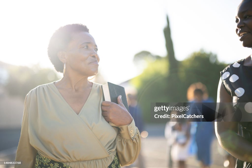 Happy senior woman clutching her bible arriving at church