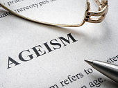 Close-up of the word Ageism and glasses nearby.