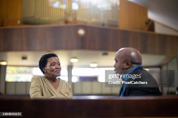 pastor talks to senior woman alone in church after service - ministry stock pictures, royalty-free photos & images