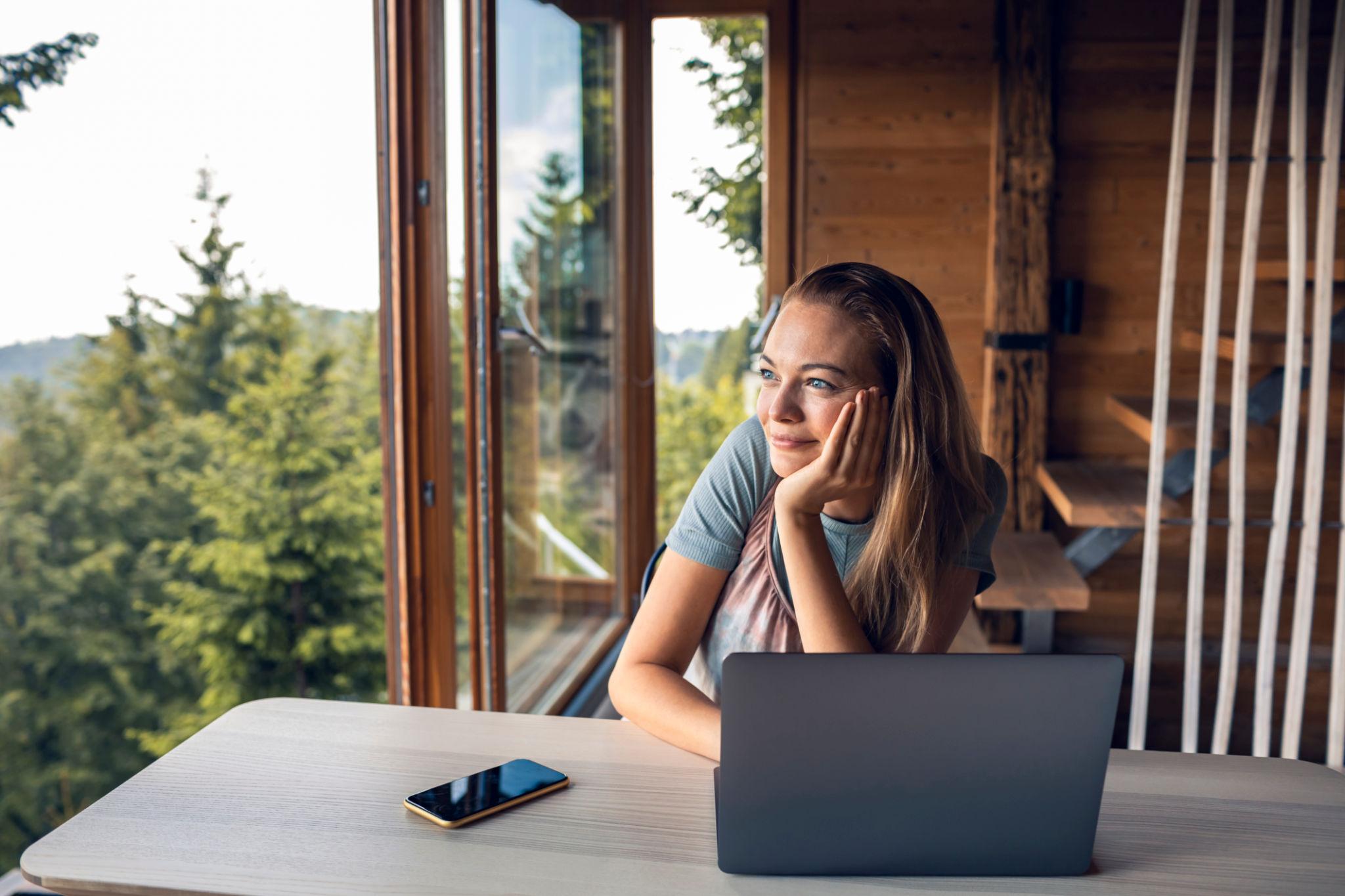 Young woman looking at the view through the window of a log cabin Young woman looking at the view through the window of a log cabin