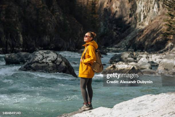 woman with a backpack on the background of a mountain river - slow stock-fotos und bilder