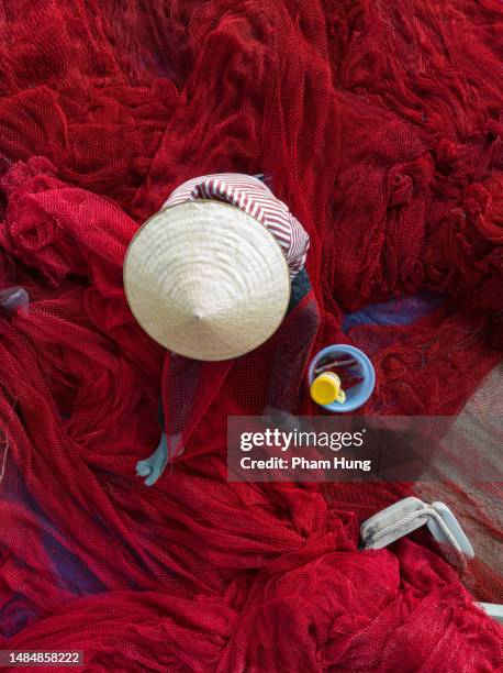 woman knitting red fishing net - vietnamese fishing net stock pictures, royalty-free photos & images