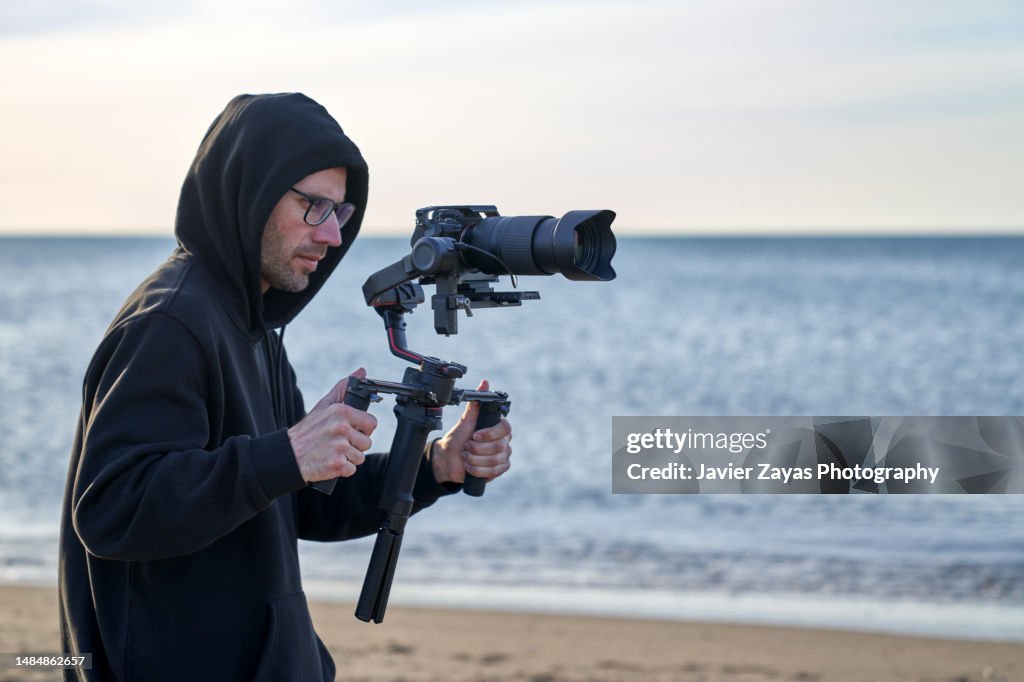 Camera Operators Outside Camera Operator Filming On The Beach Using A Stabilizer High-Res Stock ...