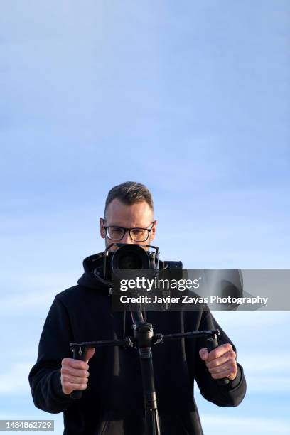 camera operator filming on the beach using a stabilizer - camera operator stock pictures, royalty-free photos & images