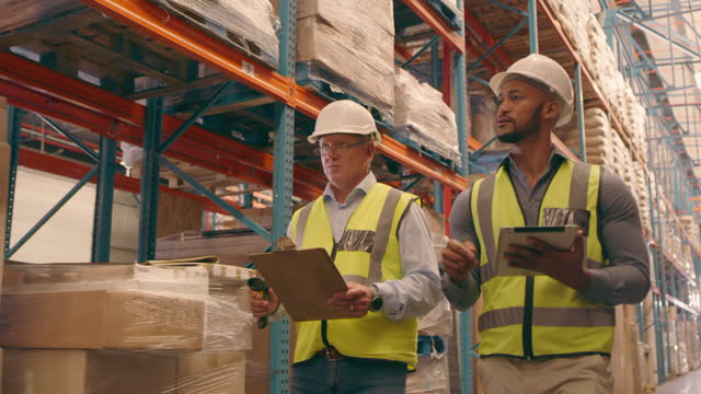 Business, men and employees with tablet, warehouse and planning for storage, inventory or discussion. Male consultants, coworkers and inspectors with clipboard, search internet or update for progress