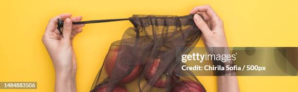 cropped hand of woman holding jeans over yellow background,romania - shopping coloured background stock pictures, royalty-free photos & images