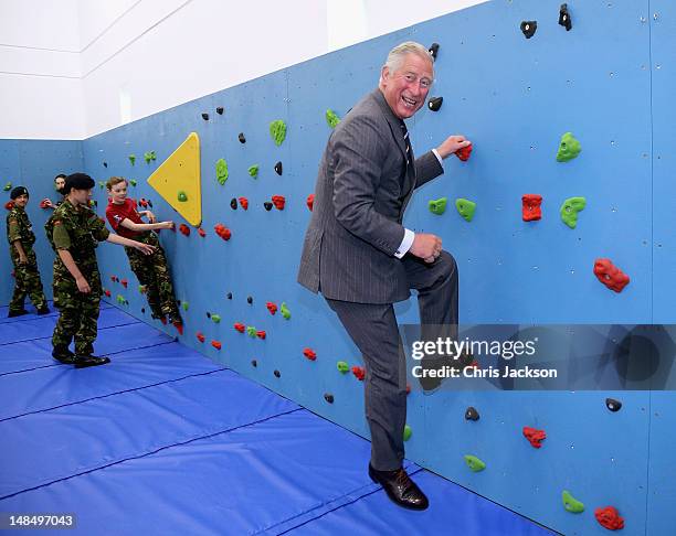 Prince Charles, Prince of Wales climbs on the new traversing wall in the new gym at Grainville Secondary School on July 18, 2012 in St Helier, United...