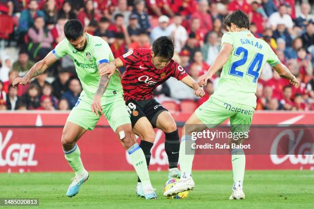 Kang-in Lee of RCD Mallorca competes for the ball with Gonzalo Villar of Getafe CF and Omar Alderete of Getafe CF during the LaLiga Santander match...