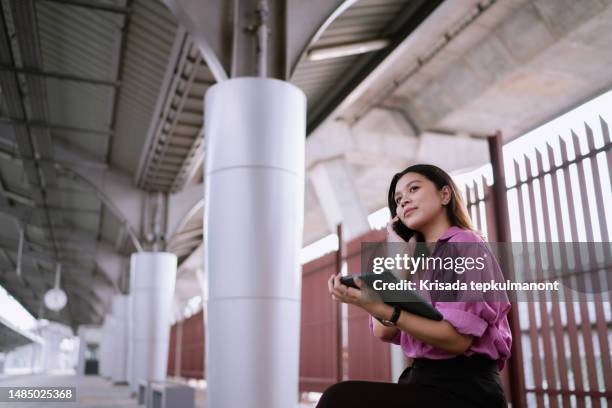 asian woman working on digital tablet while waiting for train on business trip. - commuter benefits stock pictures, royalty-free photos & images