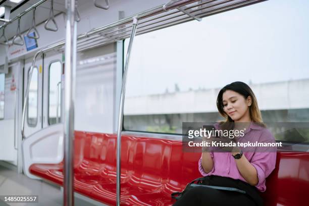 asian woman using phone while on business trip in rapid transit. - commuter benefits stock pictures, royalty-free photos & images