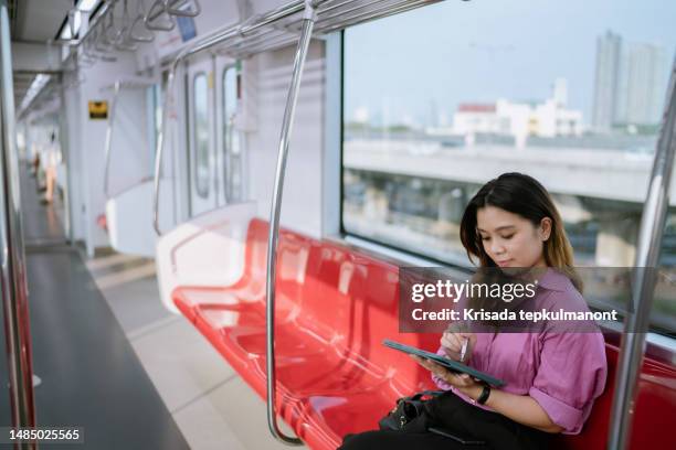 asian woman working on digital tablet during travel to work at client's office. - commuter benefits stock pictures, royalty-free photos & images