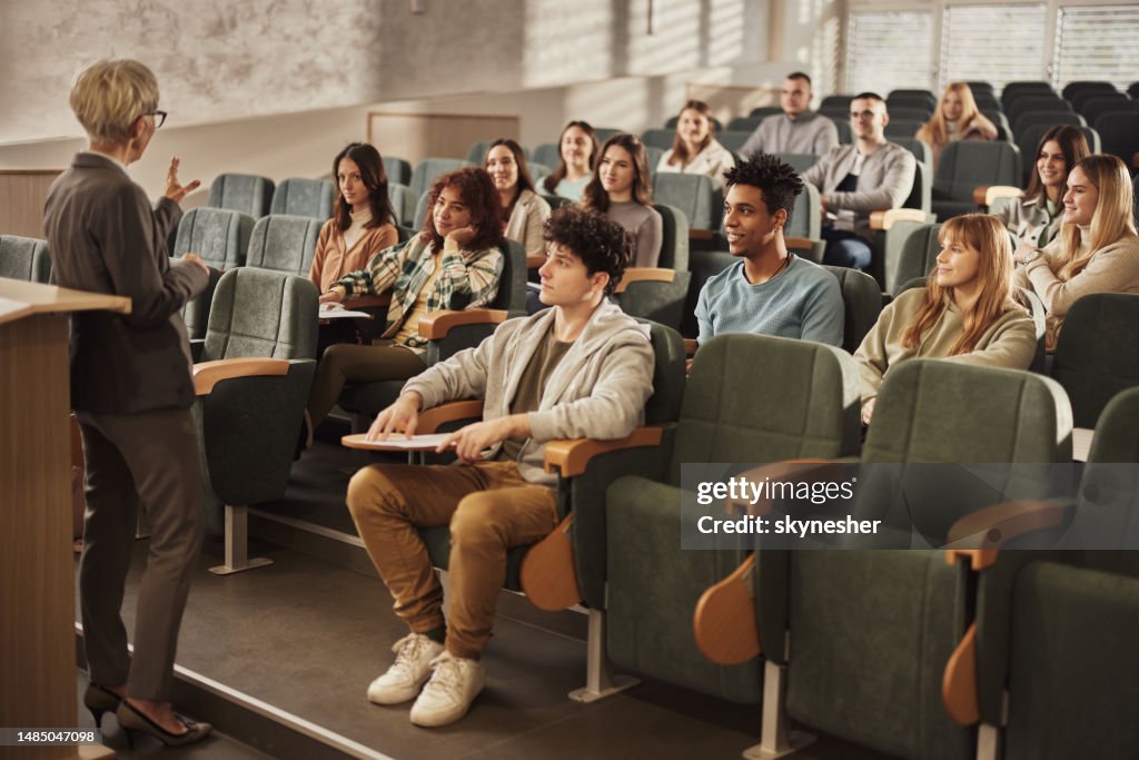 Studenti universitari che ascoltano il loro insegnante anziano in una classe in aula.