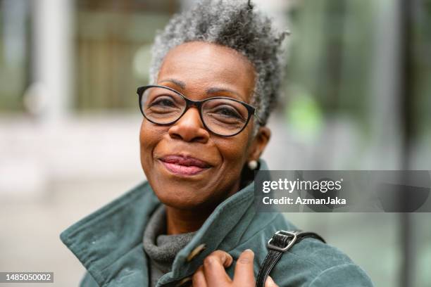 portrait of a senior adult black female on a city street looking at the camera - portrait winter stock pictures, royalty-free photos & images