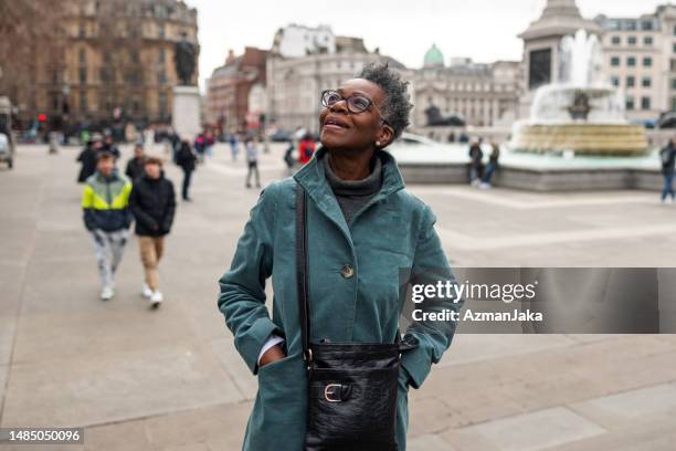 turista negra adulta mayor mirando a su alrededor y admirando los monumentos históricos de londres - mirar alrededor fotografías e imágenes de stock