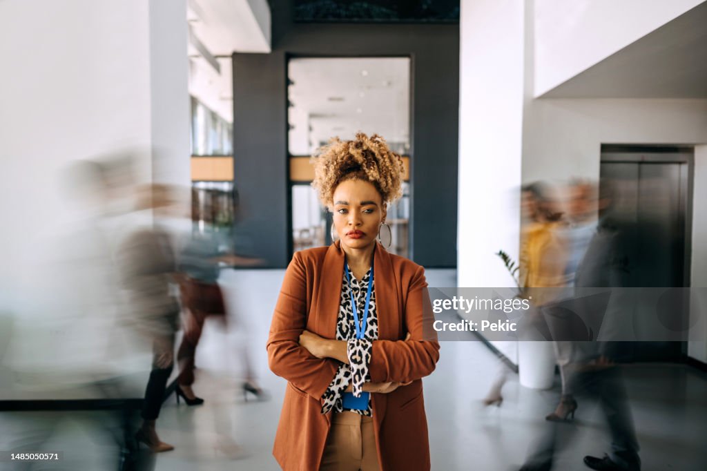 Portrait of a smiling businesswoman with people in blurred motion behind her