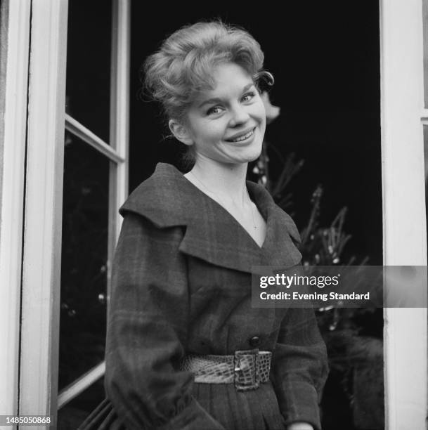 British singer and actress Sally Smith pictured with a Christmas tree in the background on December 24th, 1959.