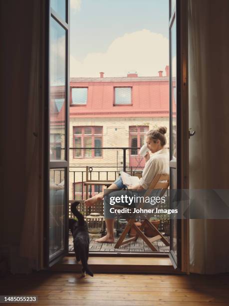 woman reading book on balcony - balcony reading stock pictures, royalty-free photos & images